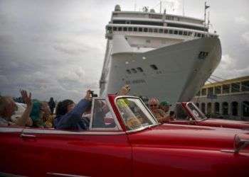 Turistas que recorren La Habana pasan por delante de un crucero atracado en el puerto de la capital de Cuba. Foto: Ramón Espinosa / AP.