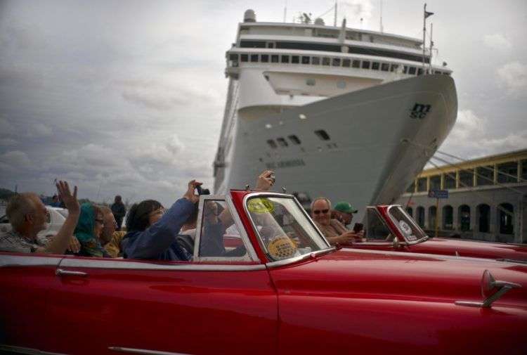 Turistas que recorren La Habana pasan por delante de un crucero atracado en el puerto de la capital de Cuba. Foto: Ramón Espinosa / AP.