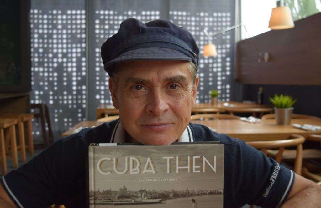 El coleccionista de fotos de Cuba Ramiro A. Fernández posando junto a su libro "Cuba Then" durante una entrevista con Efe. Foto: Jorge Ignacio Pérez / EFE.