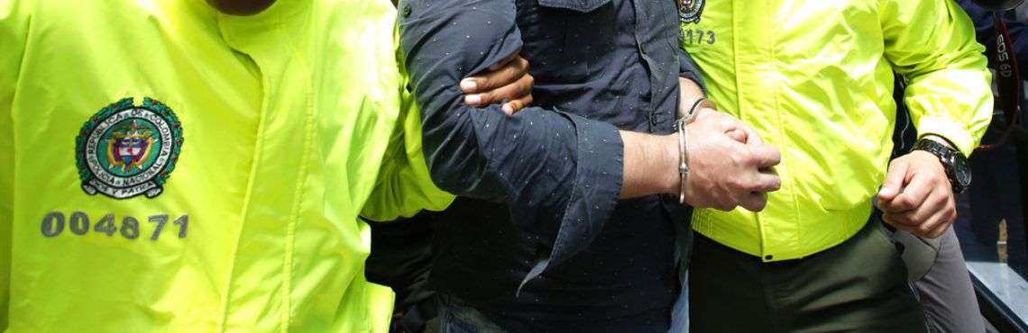 Dos policías escoltan al cubano Raúl Gutiérrez a un tribunal donde los fiscales le pidieron al juez que ordene su detención bajo cargos de terrorismo y asociación ilícita en Bogotá. Foto: Fernando Vergara / AP.