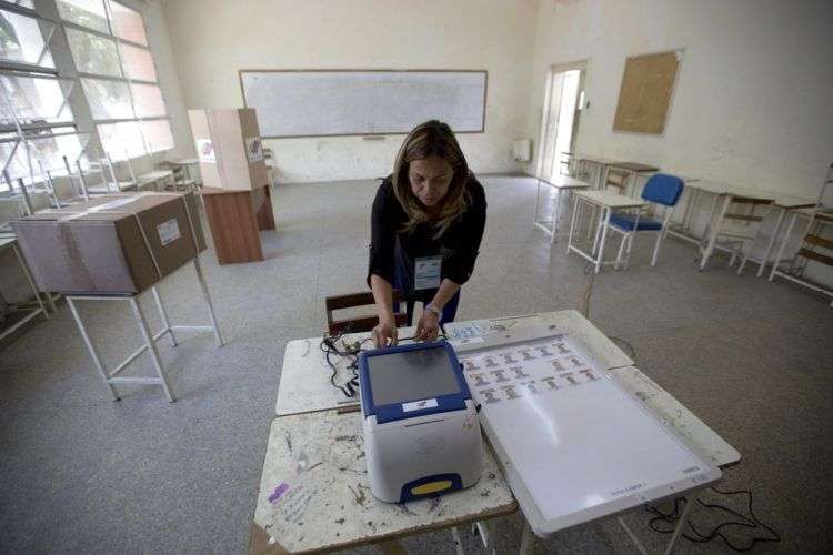 Una empleada del Consejo Electoral venezolano prepara una máquina de votación en un centro electoral en Caracas. Foto: Fernando Llano / AP.