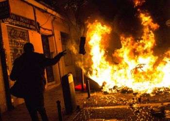 Un manifestante arroja basura a una barricada en llamas en Lavapiés, un vecindario de Madrid, España. Foto: Alejandro Martínez Velez / AP.