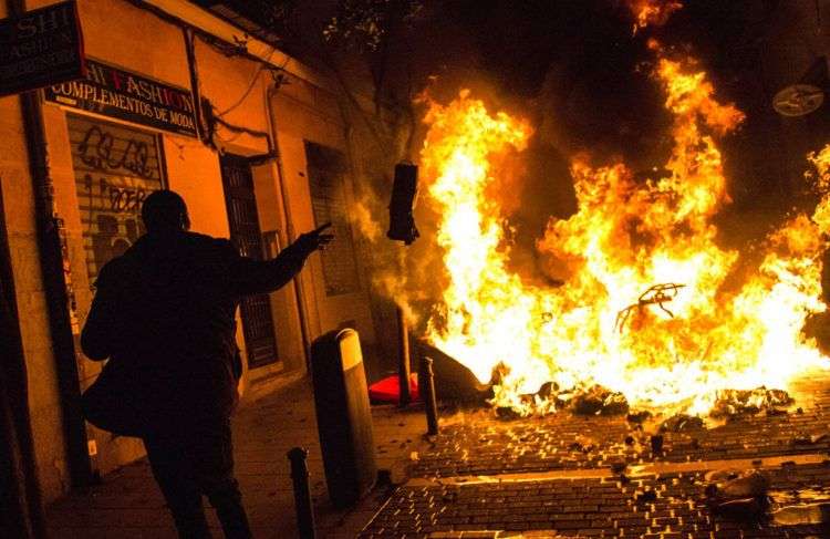 Un manifestante arroja basura a una barricada en llamas en Lavapiés, un vecindario de Madrid, España. Foto: Alejandro Martínez Velez / AP.