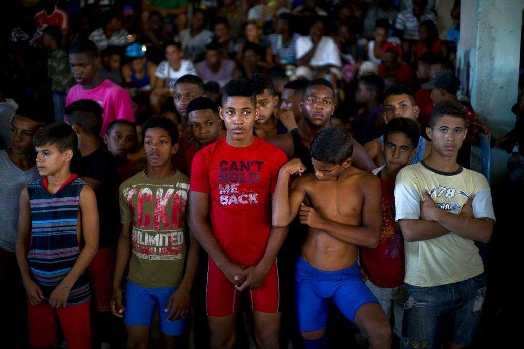 Jóvenes luchadores escuchan la oración de un sacerdote en la ceremonia de apertura de una competición de lucha de nivel aficionado en Chicharrones, Santiago de Cuba. Foto: Ramón Espinosa / AP.