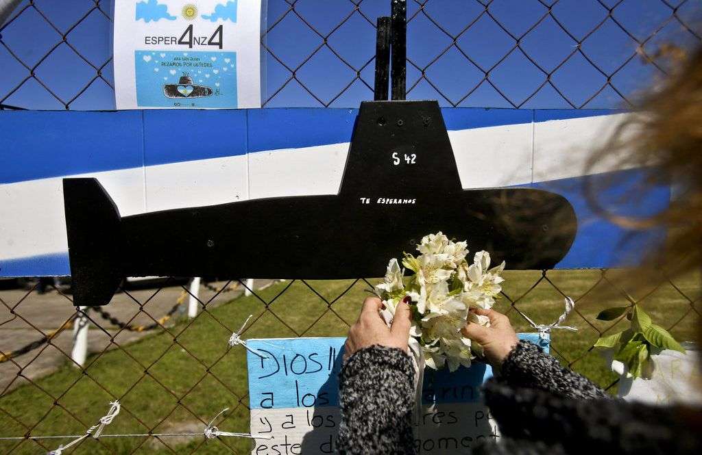 Una mujer coloca flores sobre una imagen recortada del submarino ARA San Juan en la valla de la base naval en Mar de Plata, Argentina. Foto: Esteban Felix / AP.