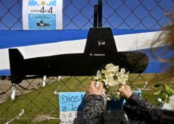 Una mujer coloca flores sobre una imagen recortada del submarino ARA San Juan en la valla de la base naval en Mar de Plata, Argentina. Foto: Esteban Felix / AP.
