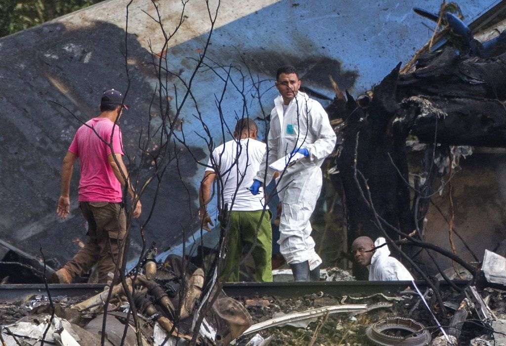 Forenses y agentes del ministerio del Interior remueven los restos de un Boeing 737 que cayó en un campo de yuca con más de 100 personas a bordo poco después de despegar de La Habana, Cuba, 18 de mayo de 2018. Foto: Desmond Boylan/AP.