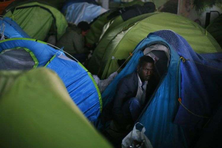 Un inmigrante espera junto a su tienda de campaña durante el desalojo de un asentamiento improvisado en París, el 30 de mayo de 2018. Foto: Thibault Camus/AP.