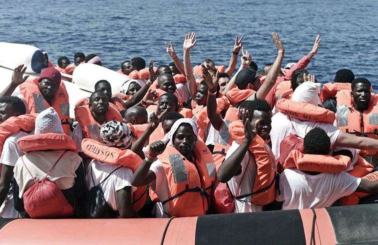 Migrantes saludan durante su traslado del barco Aquarius a otro de la Guardia Costera italiana, en el Mar Mediterráneo. Foto: Kenny Karpov / SOS Mediterranee vía AP.