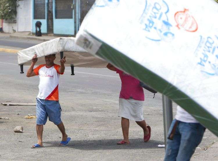 Varias personas se alejan con colchones que acaban de robar de una tienda en Managua, Nicaragua, el domingo 22 de abril de 2018. (AP Foto/Alfredo Zúñiga)