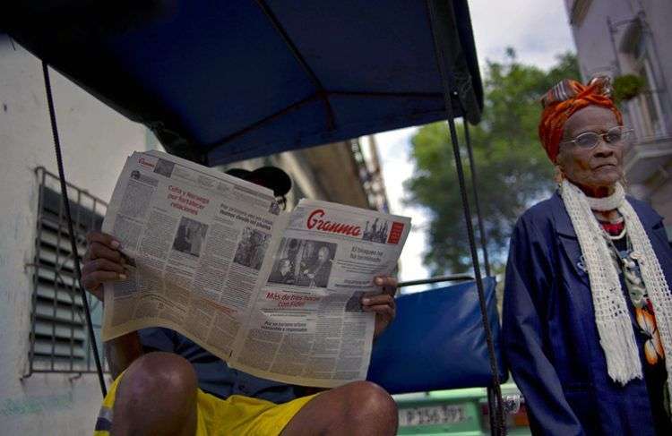 En esta imagen de archivo, tomada el 3 de febrero 2015, un hombre lee un ejemplar de Granma, diario oficial del Comité Central del Partido Comunista de Cuba, mientras una mujer pasa por su lado, en La Habana vieja. Foto: Ramon Espinosa / AP / Archivo.