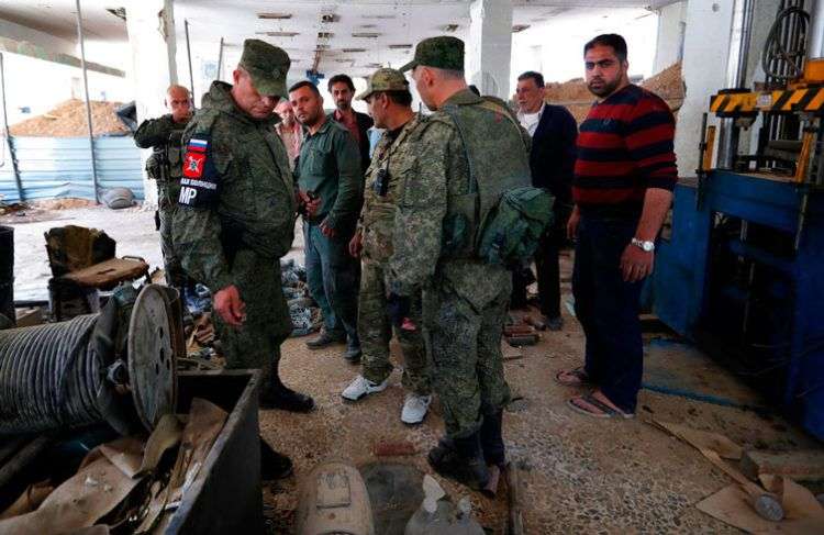 Oficiales de la policía militar rusa revisan las armas que dejaron atrás los miembros del grupo Ejército del Islam en uno de sus centros de producción en la localidad de Douma, escenario de un presunto ataque con armas químicas, cerca de Damasco. Foto: Hassan Ammar / AP.