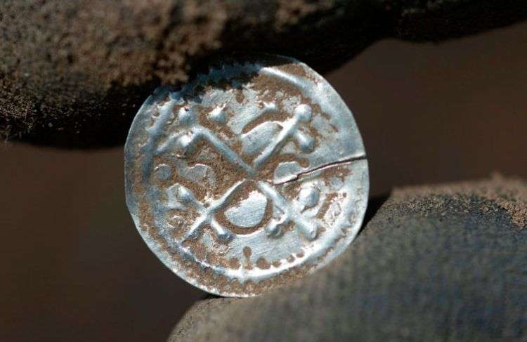 Un arqueólogo muestra una antigua moneda danesa hallada en un tesoro en la isla alemana de Rueguen en el Báltico. Foto: Stefan Sauer / dpa vía AP.