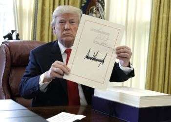 El presidente Donald Trump muestra una hoja con su firma con la que promulgó un paquete de reforma fiscal de 1,5 billonoes de dólares el viernes 22 de diciembre de 2017, en la Oficina Oval de la Casa Blanca en Washington. Foto: Evan Vucci / AP.