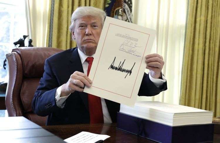 El presidente Donald Trump muestra una hoja con su firma con la que promulgó un paquete de reforma fiscal de 1,5 billonoes de dólares el viernes 22 de diciembre de 2017, en la Oficina Oval de la Casa Blanca en Washington. Foto: Evan Vucci / AP.