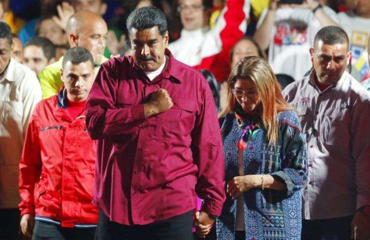 El presidente de Venezuela, Nicolás Maduro, se lleva el puño al corazón a su llegada, acompañado por su esposa Cilia Flores, a un acto con seguidores después de su reelección para un segundo mandato en las elecciones presidenciales, en Caracas, Venezuela, el 20 de mayo de 2018. Foto: Ariana Cubillos/AP.