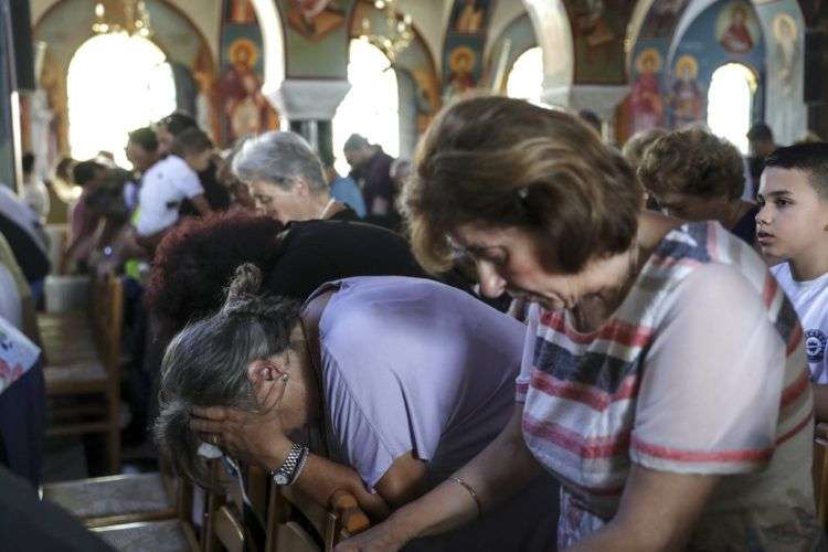 Fieles ortodoxos asisten a un funeral por las víctimas de un incendio, dentro de una iglesia en la localidad de Mati, al este de Atenas, el 29 de julio de 2018. Foto: Yorgos Karahalis/AP.