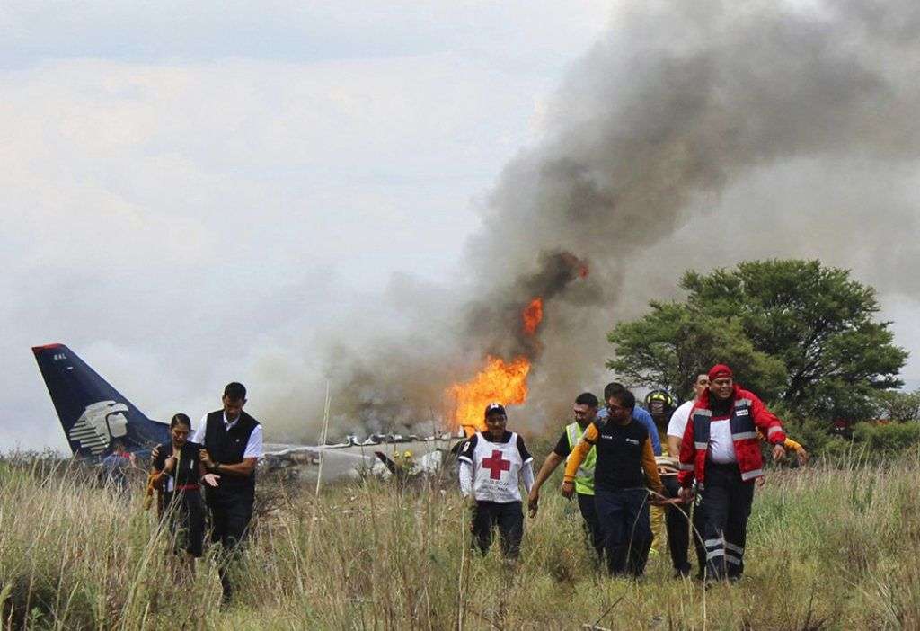 Miembros de la Cruz Roja y rescatistas llevan a una persona herida en una camilla luego del desplome de un avión comercial de Aeroméxico en las inmediaciones del aeropuerto de Durango, México, el martes 31 de julio de 2018. Foto: Cruz Roja de Durango vía AP.