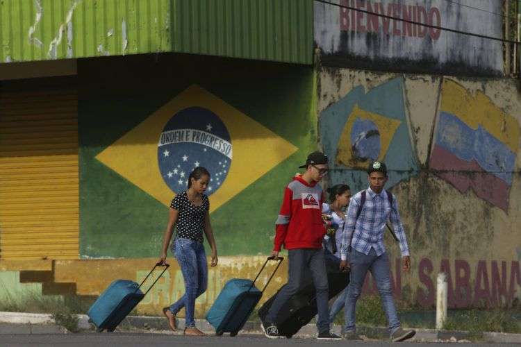 Venezolanos avanzan con su equipaje tras cruzar la frontera entre Brasil y Venezuela en la ciudad de Pacaraima, estado brasileño de Roraima, en marzo de 2018. Foto: Eraldo Peres / AP.