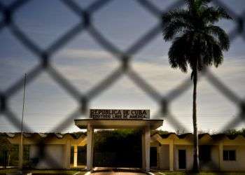 Un edificio con la leyenda "República de Cuba. Territorio Libre de América", detrás de una valla que marca la frontera con la Base Naval de Estados Unidos en la Bahía de Guantánamo. Foto: Ramón Espinosa / AP.