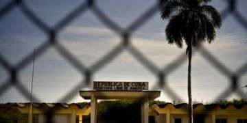 Un edificio con la leyenda "República de Cuba. Territorio Libre de América", detrás de una valla que marca la frontera con la Base Naval de Estados Unidos en la Bahía de Guantánamo. Foto: Ramón Espinosa / AP.