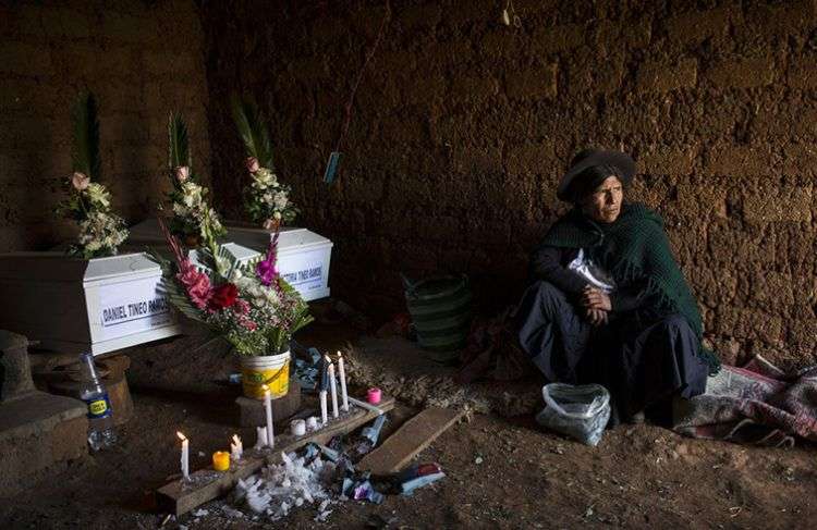 En imagen del 15 de agosto de 2018, Marta Tineo Espinosa se sienta al lado de los féretros de sus parientes, que murieron a manos del grupo armado Sendero Luminoso y el ejército peruano en 1984, en el día de su entierro en Tantana, en la provincia de Ayacucho, Perú. Foto: Rodrigo Abd / AP.
