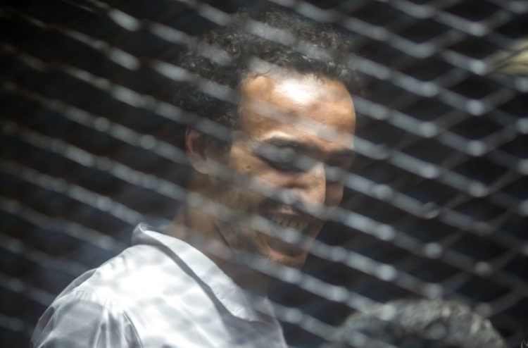Mahmoud Abu Zaid, un fotoperiodista conocido como "Shawkan" y cuya detención ha sido denunciada por grupos de derechos humanos en su país y en el extranjero, es visto detrás de una malla metálica en un tribunal en El Cairo, el sábado 8 de septiembre de 2018. Foto: Roger Anis / AP.