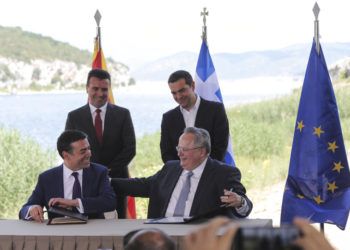 El primer ministro de Grecia, Alexis Tsipras (atrás, derecha), y su homólogo de Macedonia, Zoran Zaev (atrás, izquierda), observan mientras el ministro griego de Exteriores, Nikos Kotzias (derecho), y su contraparte macedonia, Nikola Dimitrov, firman un acuerdo para el nuevo nombre de Macedonia en la localidad de Psarades, en Grecia el 17 de junio de 2018. Foto: Yorgos Karahalis / AP.
