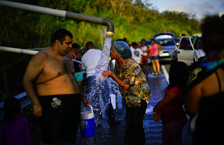 Residentes de Utuado, Puerto Rico, se aglomeran frente a tuberías que traían agua de un riachuelo el 14 de octubre del 2017, tras el paso del huracán María que causó devastación en la isla. Foto: Ramón Espinosa / AP / Archivo.