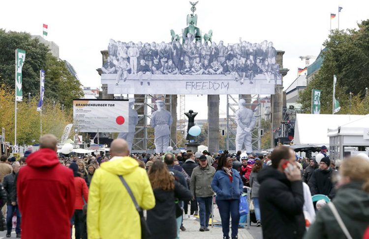 Visitantes caminan frente a la Puerta de Brandenburgo durante los festejos del Día de la Unificación en Berlín, Alemania, el miércoles 3 de octubre de 2018. Foto: Michael Sohn / AP.