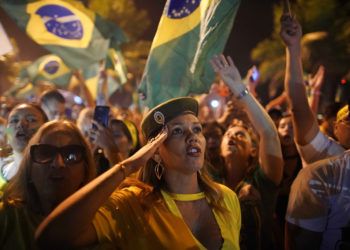 Una simpatizante de Jair Bolsonaro saluda durante la celebración de su triunfo en las elecciones presidenciales afuera de la residencia del candidato en Río de Janeiro, Brasil, el 28 de octubre de 2018. Foto: Leo Correa / AP.