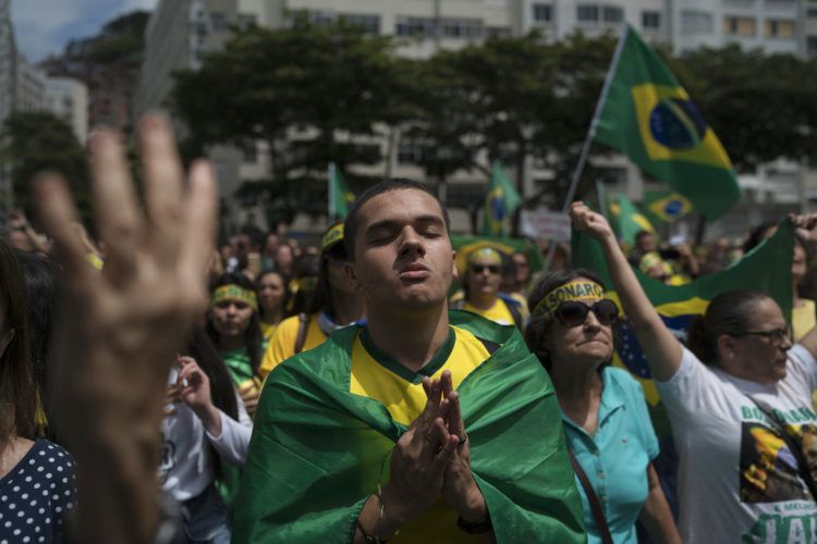 Una multitud escucha el himno nacional en el acto de campaña del candidato presidencial ultraderechista Jair Bolsonaro en Río de Janeiro, el domingo 21 de octubre de 2018. Foto: Leo Correa / AP.