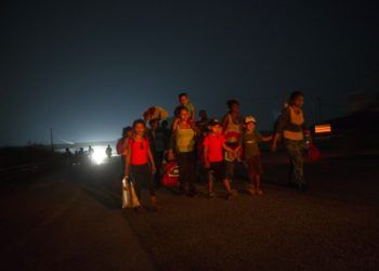 Una familia camina junto a otros migrantes centroamericanos en una caravana de miles de personas que lentamente se dirige a la frontera entre México y Estados Unidos, en las afueras de Arriaga, México, antes del amanecer del sábado 27 de 2018. (AP Foto/Rodrigo Abd)