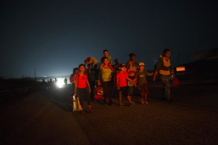 Una familia camina junto a otros migrantes centroamericanos en una caravana de miles de personas que lentamente se dirige a la frontera entre México y Estados Unidos, en las afueras de Arriaga, México, antes del amanecer del sábado 27 de 2018. (AP Foto/Rodrigo Abd)