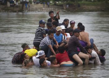 Un grupo de migrantes centroamericanos cruzan el río Suchiate en una balsa hecha de llantas de tractor y tablas, en la frontera entre Guatemala y México, en Ciudad Hidalgo, México, 20 de octubre de 2018. Foto: Moises Castillo / AP.