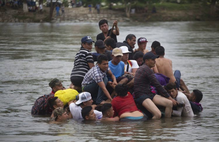 Un grupo de migrantes centroamericanos cruzan el río Suchiate en una balsa hecha de llantas de tractor y tablas, en la frontera entre Guatemala y México, en Ciudad Hidalgo, México, 20 de octubre de 2018. Foto: Moises Castillo / AP.