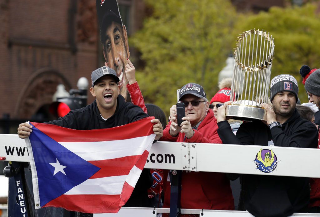El manager Alex Cora exhibe la bandera de Puerto Rico durante el desfile de celebración en Boston. (AP Foto/Elise Amendola)