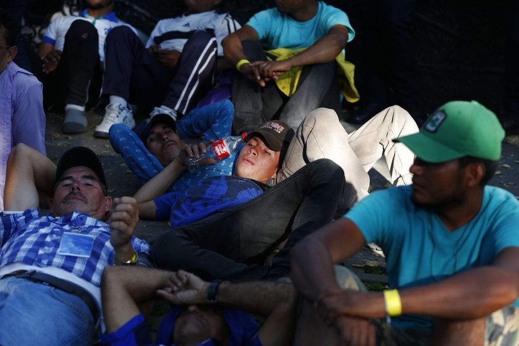 Decenas de migrantes centroamericanos, representando a los miles que forman parte de una caravana que intenta llegar a la frontera de Estados Unidos, descansan ante de una oficina de la agencia de derechos humanos de Naciones Unidas tras una marcha de varias horas exigiendo autobuses, en la Ciudad de México, el 8 de noviembre de 2018. (AP Foto/Rebecca Blackwell)