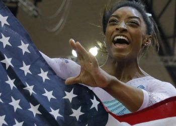 Cuatro veces campeona mundial de prueba combinada, Simone Biles, de Estados Unidos, celebra sosteniendo la bandera de su país en el Mundial de Doha, Qatar. (AP Foto/Vadim Ghirda)