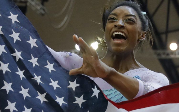 Cuatro veces campeona mundial de prueba combinada, Simone Biles, de Estados Unidos, celebra sosteniendo la bandera de su país en el Mundial de Doha, Qatar. (AP Foto/Vadim Ghirda)
