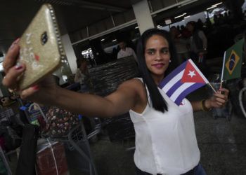 Una doctora cubana sosteniendo banderas de Cuba y Brasil se toma una selfie antes de que ella y otros médicos de su país regresen a casa desde el aeropuerto de Brasilia, Brasil, el jueves 22 de noviembre de 2018. (AP Foto/Eraldo Peres)