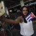 Una doctora cubana sosteniendo banderas de Cuba y Brasil se toma una selfie antes de que ella y otros médicos de su país regresen a casa desde el aeropuerto de Brasilia, Brasil, el jueves 22 de noviembre de 2018. (AP Foto/Eraldo Peres)