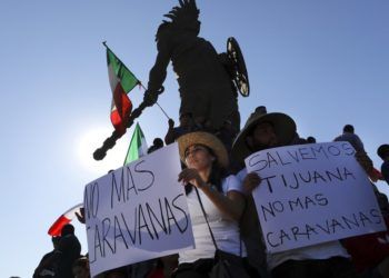Manifestantes sostienen carteles bajo la estatua del emperador azteca Cuauhtémoc como protesta contra los miles de migrantes centroamericanos que han llegado a la ciudad en Tijuana, México, el domingo 18 de noviembre de 2018. Foto: Rodrigo Abd / AP.