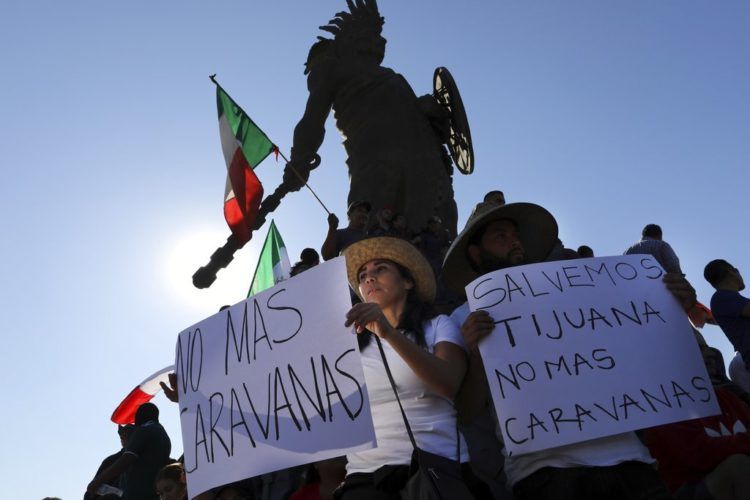 Manifestantes sostienen carteles bajo la estatua del emperador azteca Cuauhtémoc como protesta contra los miles de migrantes centroamericanos que han llegado a la ciudad en Tijuana, México, el domingo 18 de noviembre de 2018. Foto: Rodrigo Abd / AP.