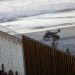 Un migrante centroamericano está sentado sobre la estructura fronteriza que separa México (izquierda) de Estados Unidos (derecha), mientras agentes fronterizos estadounidenses vigilan la escena, el 14 de noviembre de 2018, en esta imagen tomada desde Tijuana, México. (AP Foto/Gregory Bull)