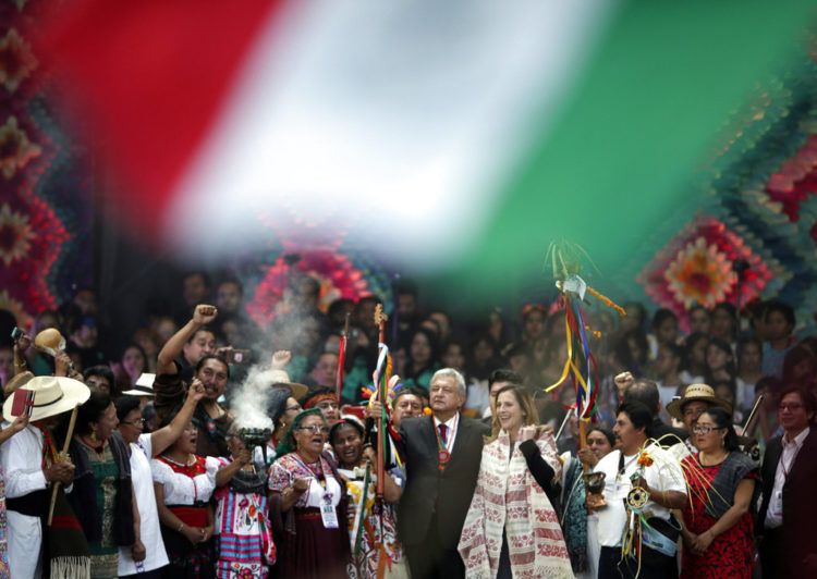 El nuevo presidente mexicano, Andrés Manuel López Obrador, al centro, sostiene un bastón de mando durante una ceremonia tradicional indígena en el Zócalo de la Ciudad de México el sábado 1ro de diciembre de 2018. A la derecha aparece de pie su esposa, Beatriz Gutiérrez Müller. Foto: Eduardo Verdugo / AP.