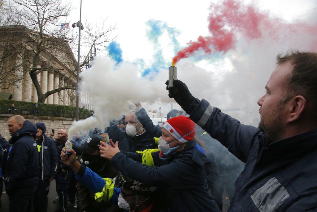 Trabajadores de ambulancias encienden bengalas en el exterior de la Asamblea Nacional francesa, en París, el 3 de diciembre de 2018. Foto: Michel Euler / AP.
