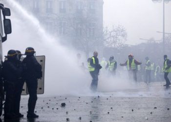 Manifestantes vestidos con chalecos amarillos se enfrentan a los cañones de agua de la policía durante una protesta cerca de la avenida de los Campos Elíseos, en París, el 1 de diciembre de 2018. Foto: Kamil Zihnioglu / AP.
