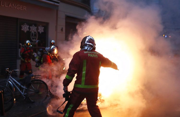 Bomberos intentan extinguir el fuego de un vehículo incendiado por manifestantes durante un enfrentamiento con policías antidisturbios en París, el sábado 8 de diciembre de 2018. Foto: Thibault Camus / AP.