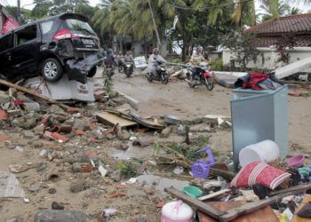 Varios motociclistas avanzan por una calle llena de escombros tras el paso de un tsunami en Anyar, Indonesia, el domingo 23 de diciembre de 23, 2018. Foto: AP.